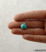 Natural Persian turquoise cabochon displayed on hand to represent real-life size and dome thickness