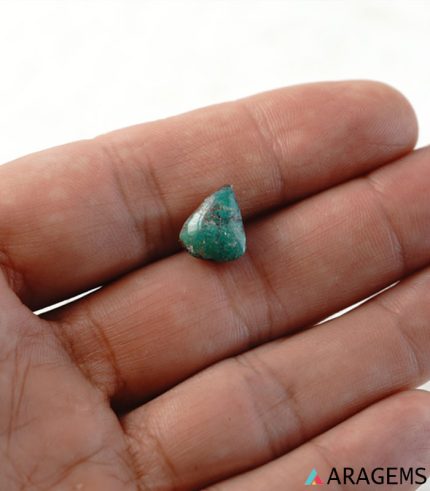 Green Iranian turquoise cabochon shown on hand to display real-life size.