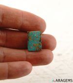 Rectangular Iranian turquoise cabochon shown on hand to display real-life size.