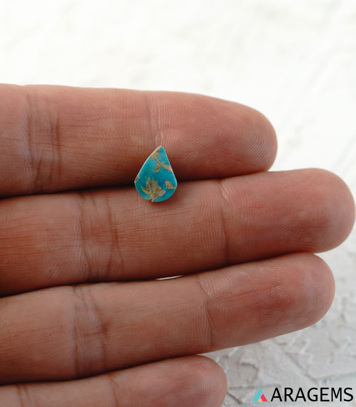 Blue Iranian turquoise cabochon shown on hand for real-life size reference.t26-Aragems