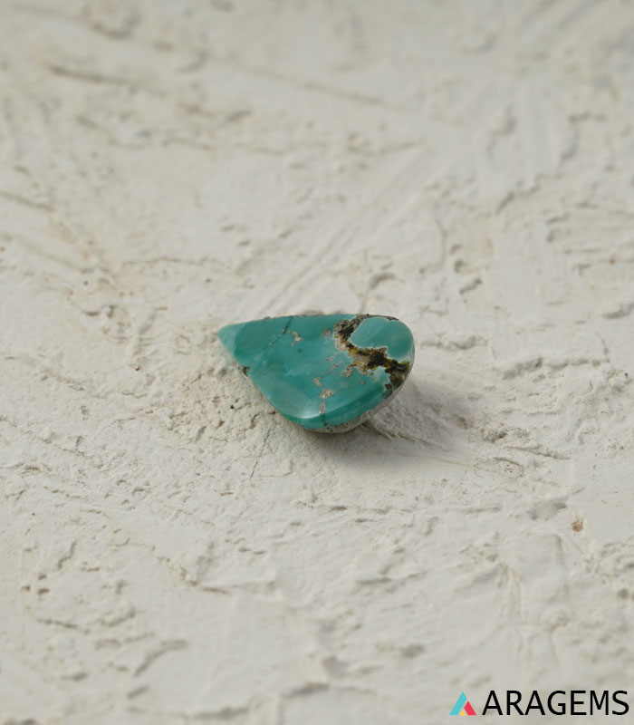 Perspective view of green-blue Persian turquoise teardrop cabochon highlighting smooth dome and natural polish.t32