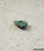 Perspective view of green Iranian turquoise teardrop cabochon highlighting polished dome and organic matrix structure.