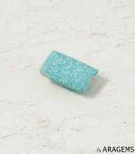 Natural Kerman turquoise rectangular cabochon on a textured white surface, angled view - T43