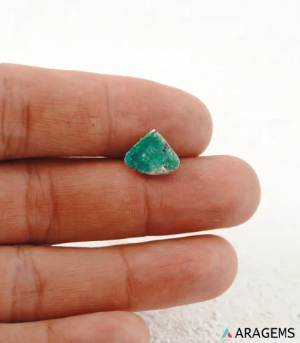 Hand holding natural green Persian turquoise triangular cabochon showing its 12 x 10 mm size - T45