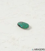 Hand holding natural green Kerman turquoise oval cabochon showing its 9 x 15 mm size - T49