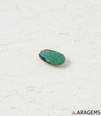 Hand holding natural green Kerman turquoise oval cabochon showing its 9 x 15 mm size - T49