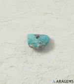 Natural blue Kerman turquoise teardrop cabochon on a textured white surface, close angle - T51