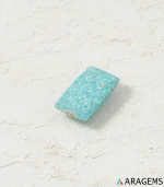 Natural light blue Kerman turquoise rectangular cabochon on a textured white surface, side angle - T43