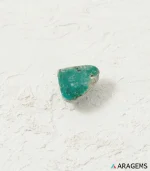 Natural green Kerman turquoise triangular cabochon on a textured white surface, angled view - T45