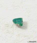 Natural green Persian turquoise triangular cabochon on a textured white surface, side angle - T45