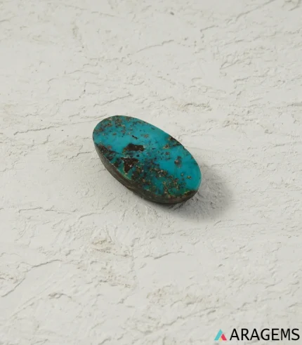 Hand holding natural Neyshabur turquoise elongated oval cabochon showing its 13 x 25 mm size - T50