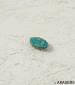 Natural blue-green Neyshabur turquoise oval cabochon on a textured white surface, angled view - T48