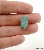 Hand holding natural green Neyshabur turquoise oval cabochon showing its 10 x 20 mm size - T44
