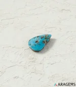 Natural Neyshabur turquoise teardrop cabochon on a textured white surface, side angle - T47