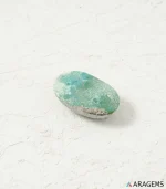 Natural green Kerman Persian turquoise oval cabochon on a textured white surface, profile view - T57