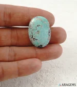 Hand holding natural green Kerman Persian turquoise oval cabochon showing its 20 x 29 mm size - T55