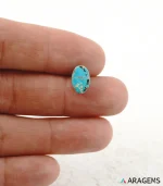 Hand holding natural blue Neyshabur turquoise oval cabochon showing its 7 x 11 mm size - T46