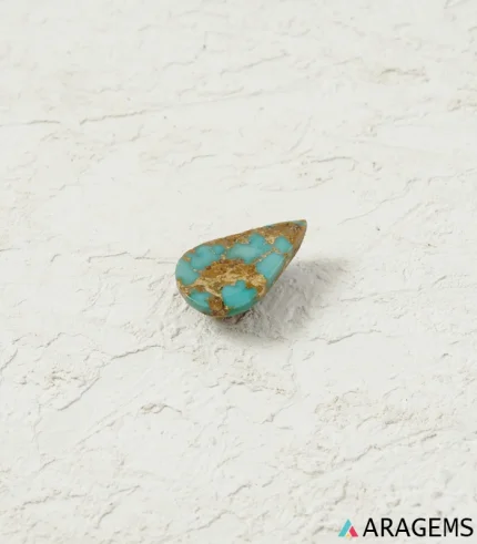 Natural blue Neyshabur turquoise teardrop cabochon on a textured white surface, close angle - T52
