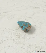 Natural Neyshabur turquoise teardrop cabochon on a textured white surface, side angle - T54