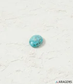 Natural Neyshabur Persian turquoise oval cabochon on a textured white surface, top view - T56