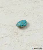 Natural blue Neyshabur turquoise oval cabochon on a textured white surface, angled view - T46