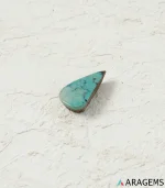 Natural teal Neyshabur turquoise teardrop cabochon on a textured white surface, close angle - T53